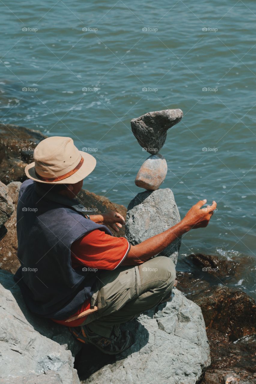 Rear view of man sitting on rock at sea
