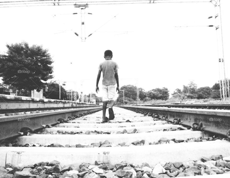 Photographs of a railway track,a photo of a boy,a photo of a railway track and a boy,a photo of a boy going on a railway track,a beautiful view of a photo,black and white beautiful photos,attractive photos of a railway track and a boy,memorabl