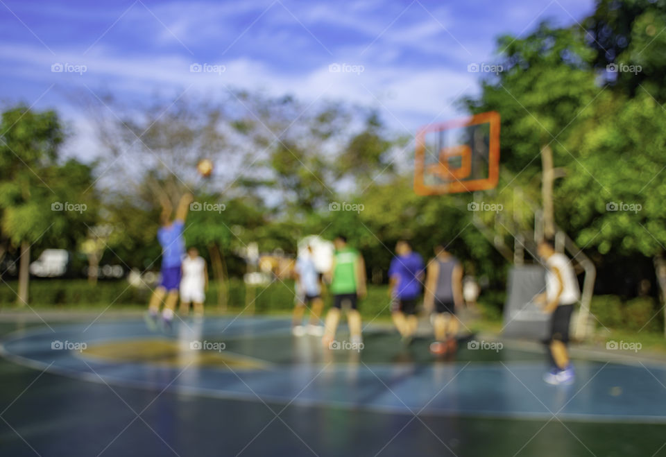 Blurry image of elderly men and teens playing basketball in the morning at BangYai Park , Nonthaburi in Thailand.