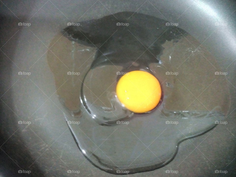 One yellow egg/egg yolk and egg white in a black pan