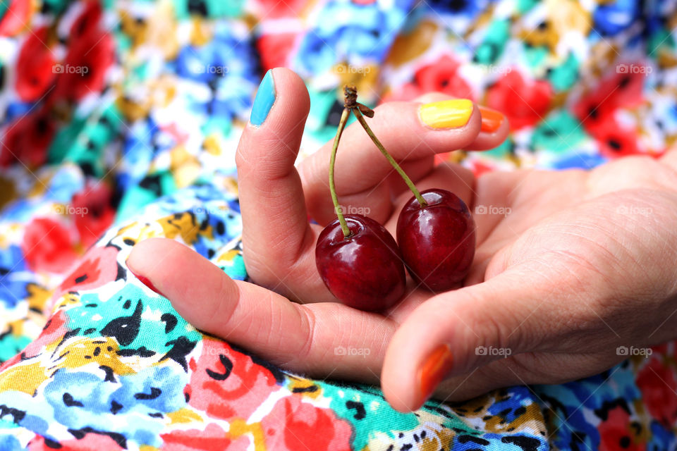 Colored nail polish and dress, a hand holding cherries