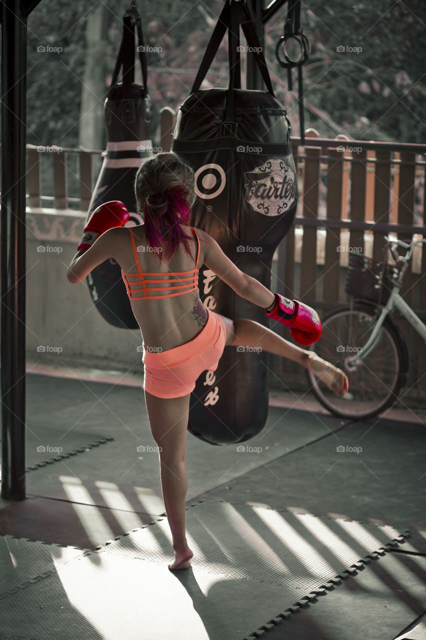 Woman kicking bag at training. Asian lady at muay Thai camp