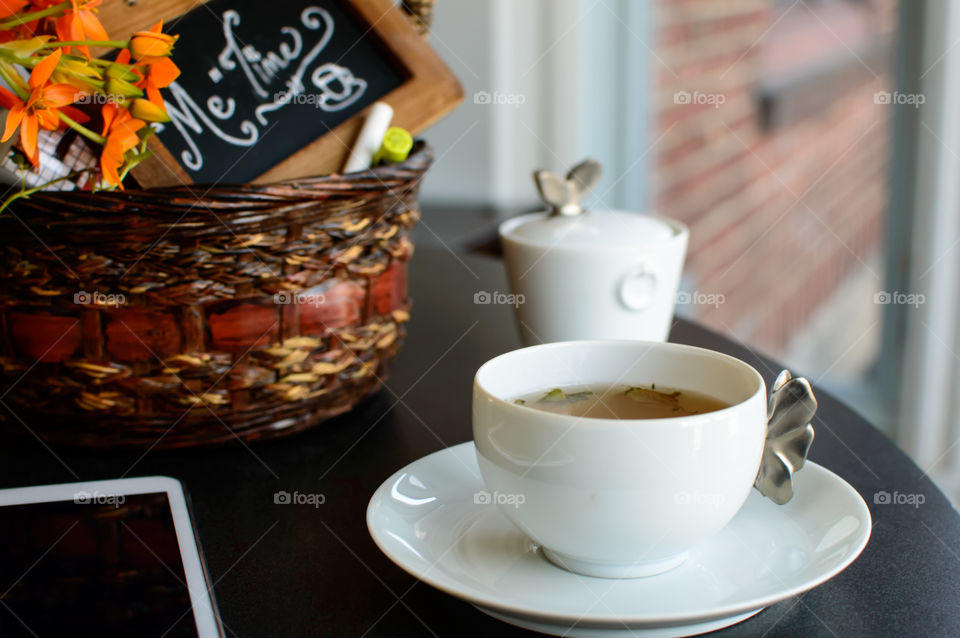 Health and self care wellness conceptual photography table with cup of tea and tablet with basket and chalk board with handwritten words "me time" on desktop near window