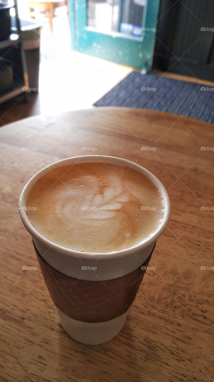 a design on top of a latte sitting on a table in a coffee shop