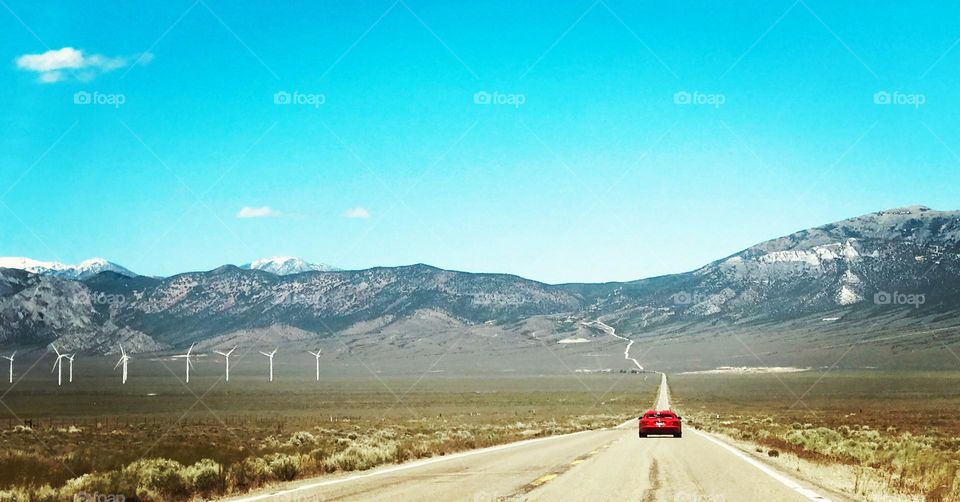 Road-trip through Americas loneliest highway red Viper sports car on road with windmills in background