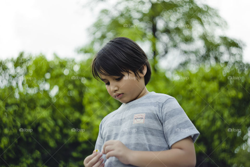 outdoor portrait of young eurasian boy on a blurry out of focus bokeh foliage background