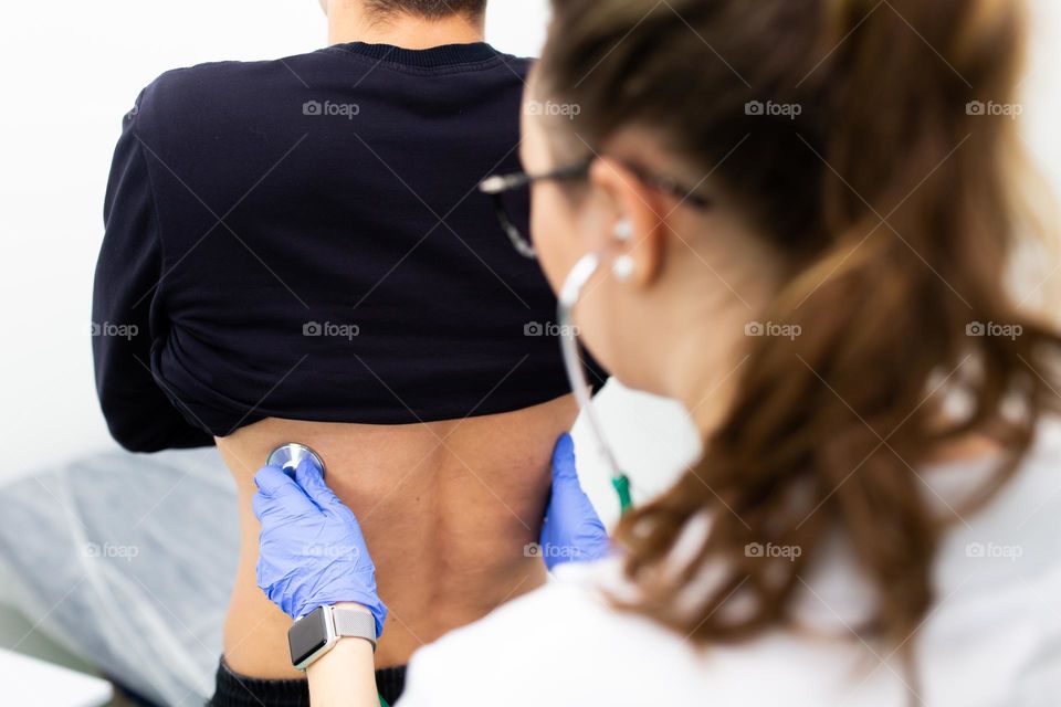 a female family doctor examines the respiratory tract with a stethoscope
