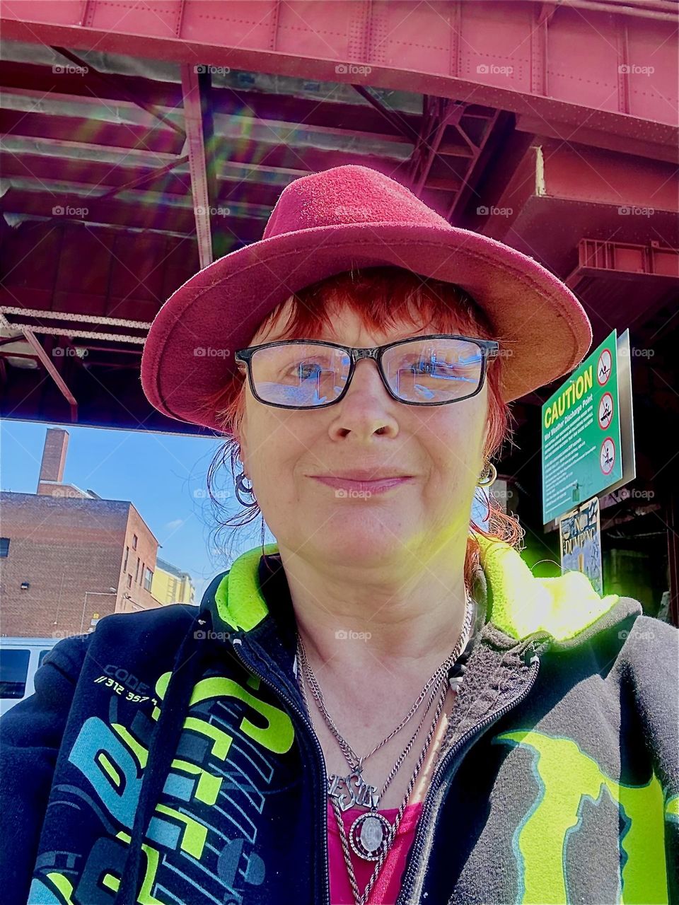 This is me, “Petra Schiller” a.k.a. “Maxine Firefox” standing in the parking lot beneath the modern art inspired “Pulaski Bridge” at “Newtown Creek” in LIC, Queens on a bright sunny day in May 2024. Hypnotic Productions