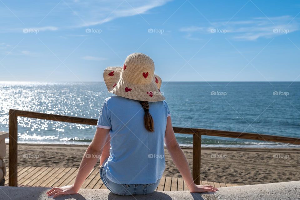 Girl in summer straw hat admire sea view.