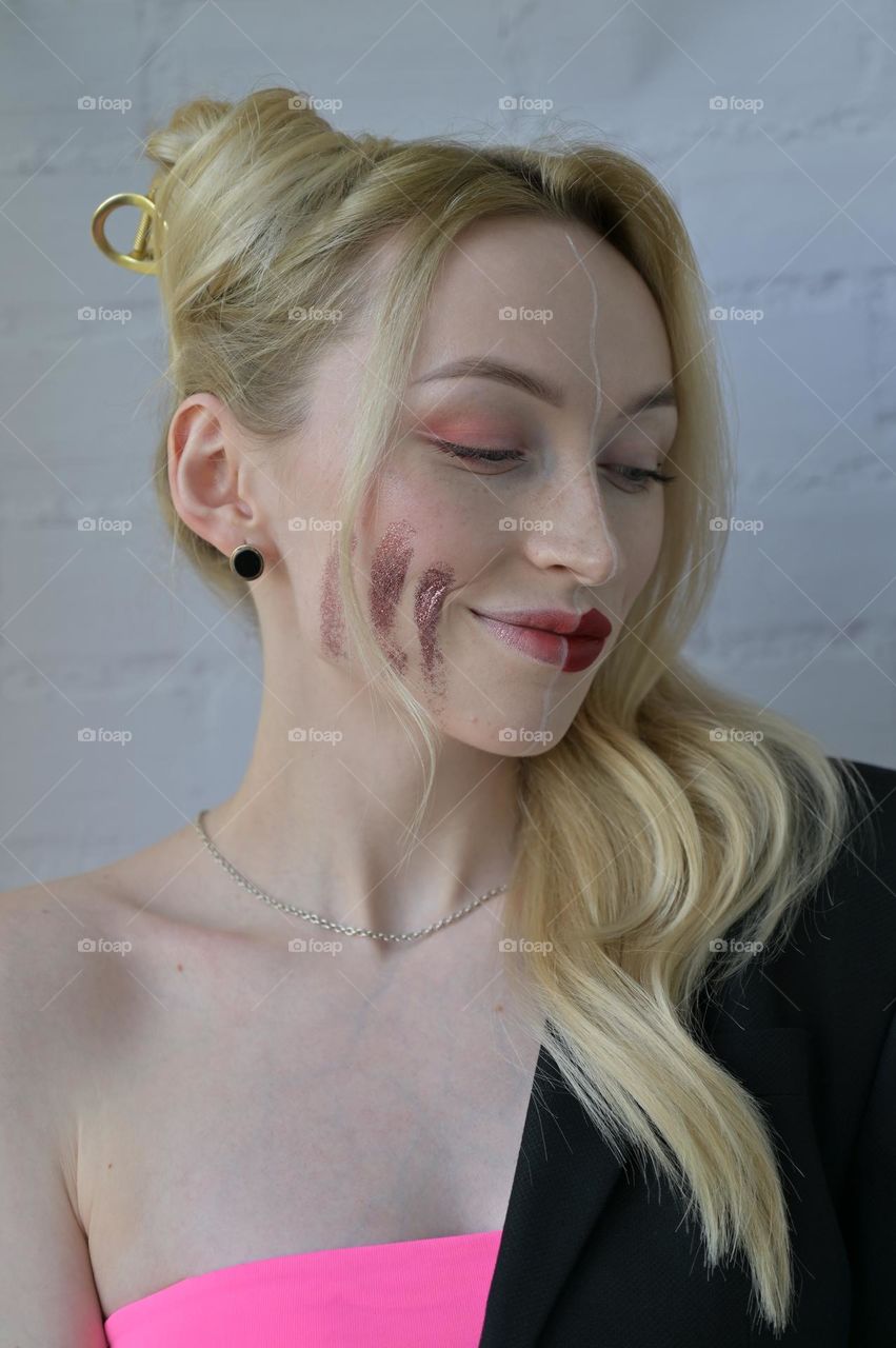 Close-up portrait of a blonde girl with different make-up on half of her face on white background