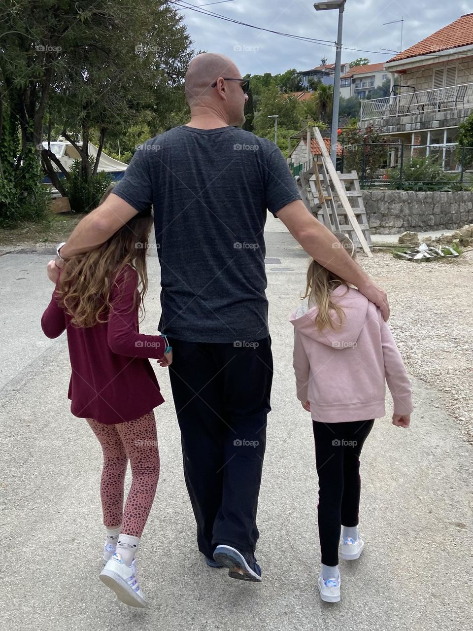 A father walking with his two daughters.