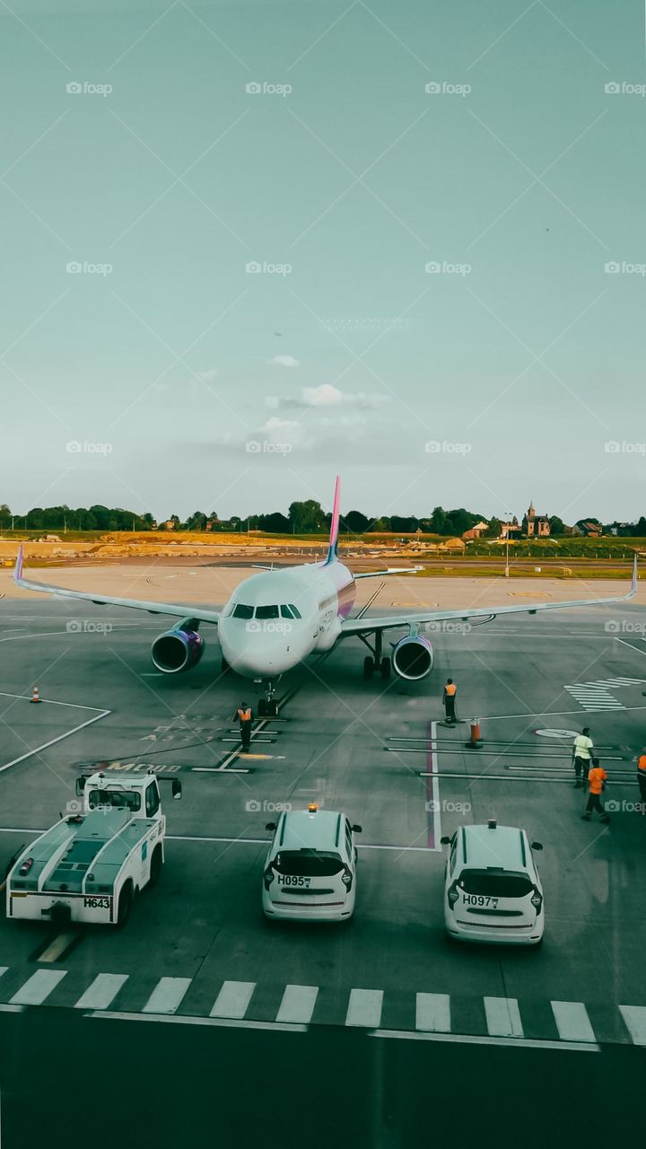 A beautiful view of a plane standing at the airport with cars next to it, close-up view from above.