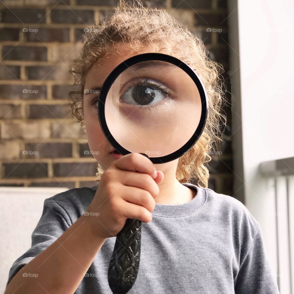 Child looking through a magnifying glass with one eye 