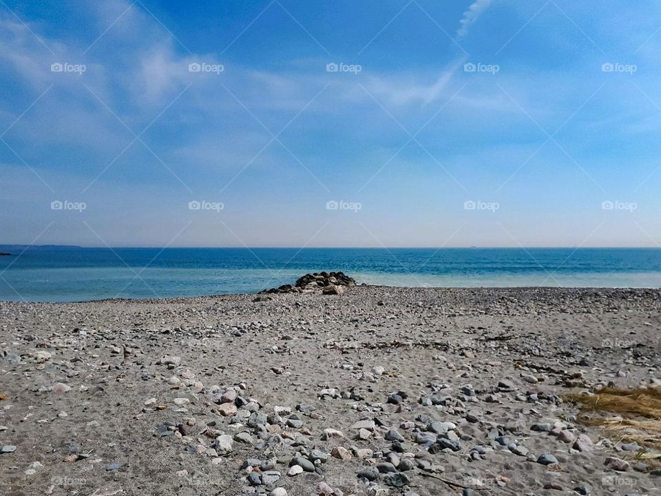 Beach and its charms.The blue sky, rocks in the sand and an endless horizon. The waves of the sea speak to the soul and nature soothes.