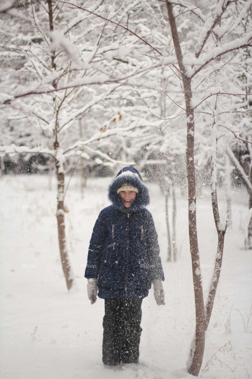 Girl laughing under snow falling from a tree