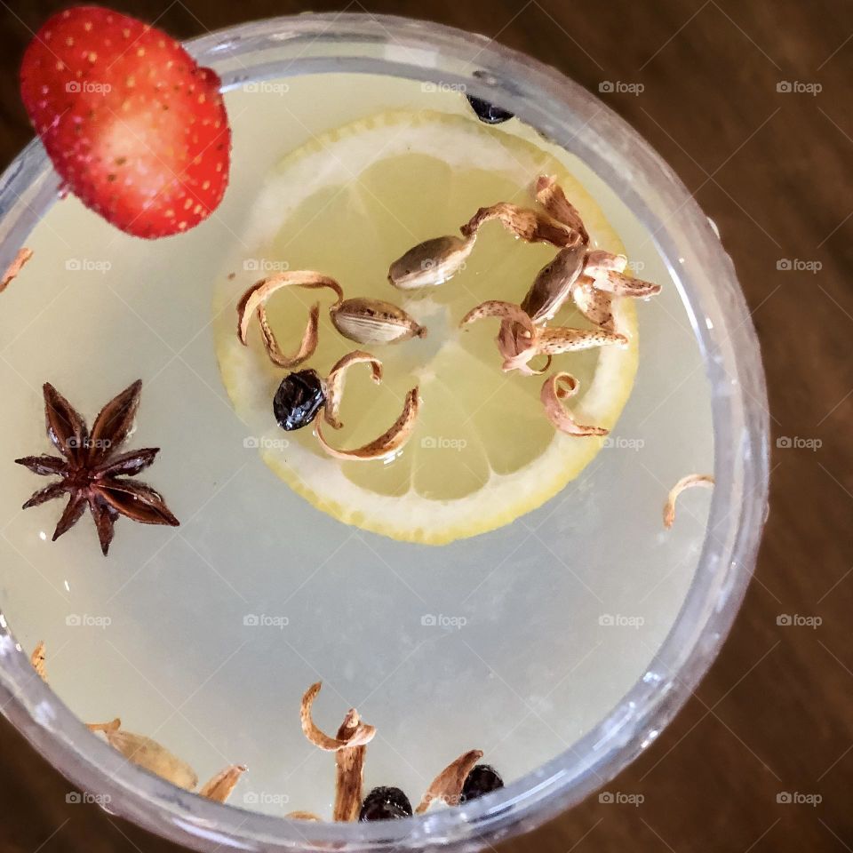 Gin & lemon viewed from above with dried orange peel, star anise and a strawberry on the side