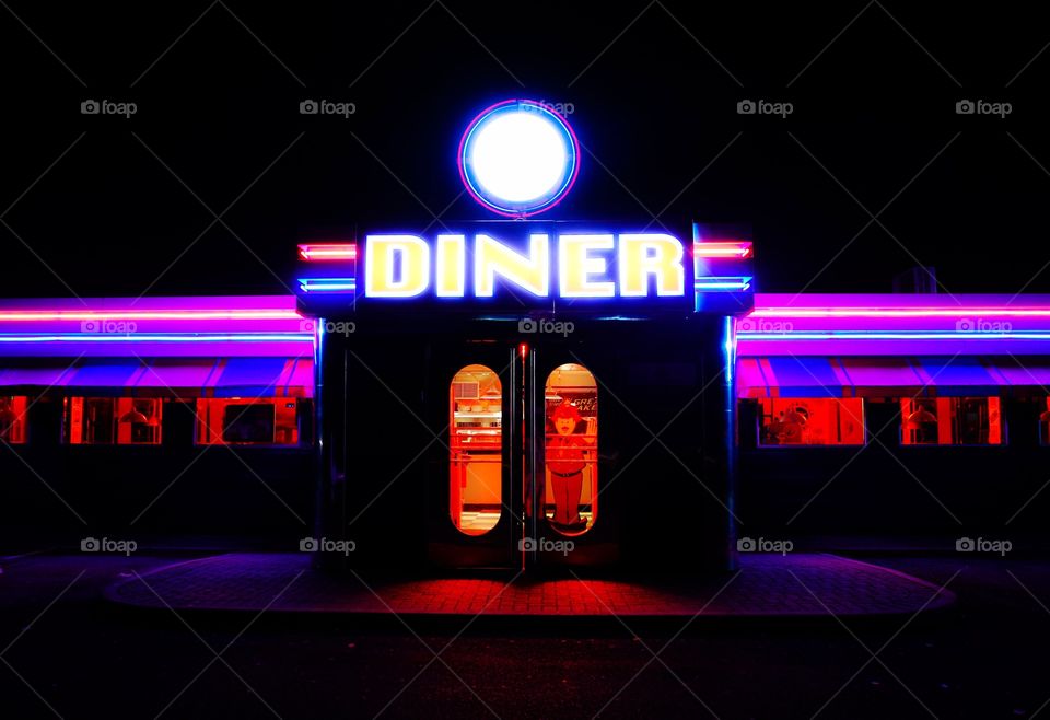 The colourful facade and exterior of a traditional American diner with brightly coloured neon lights and fluorescent colours