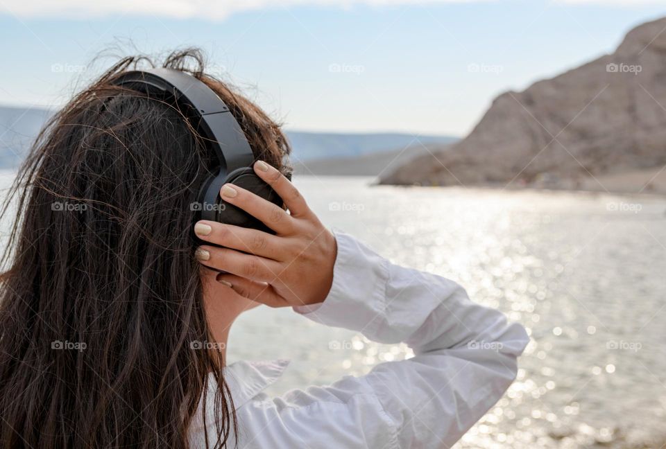 Back view of female with headphones on a beach