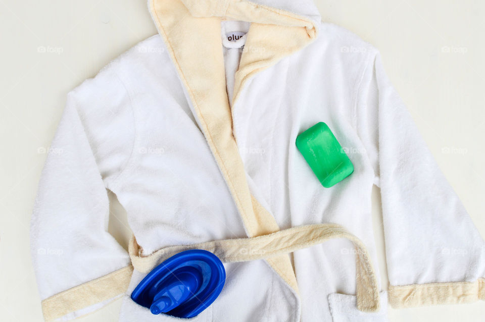 Child's bathrobe laid out with soap and a toy boat