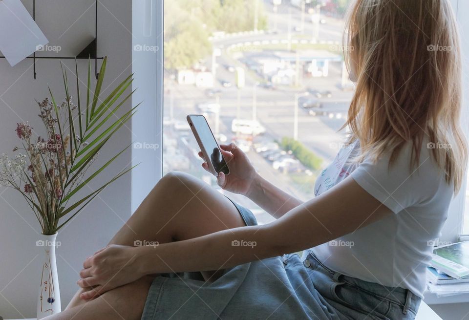 A woman sitting by the window at home 