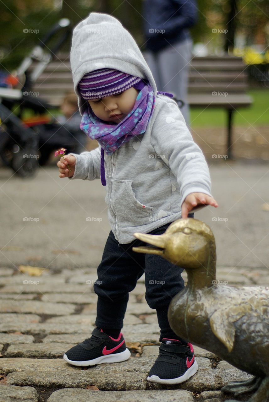 Baby girl playing with ducks statues at Boston's Public Garden