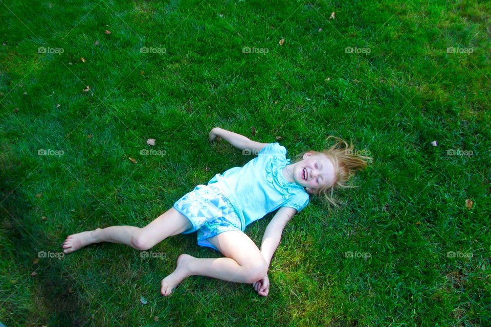 Young girl laying in the grass laughing 
