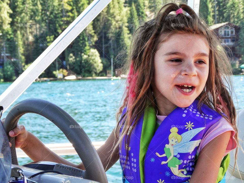 Young Girl Driving A Motorboat. Happy Young Girl Boating On A Lake
