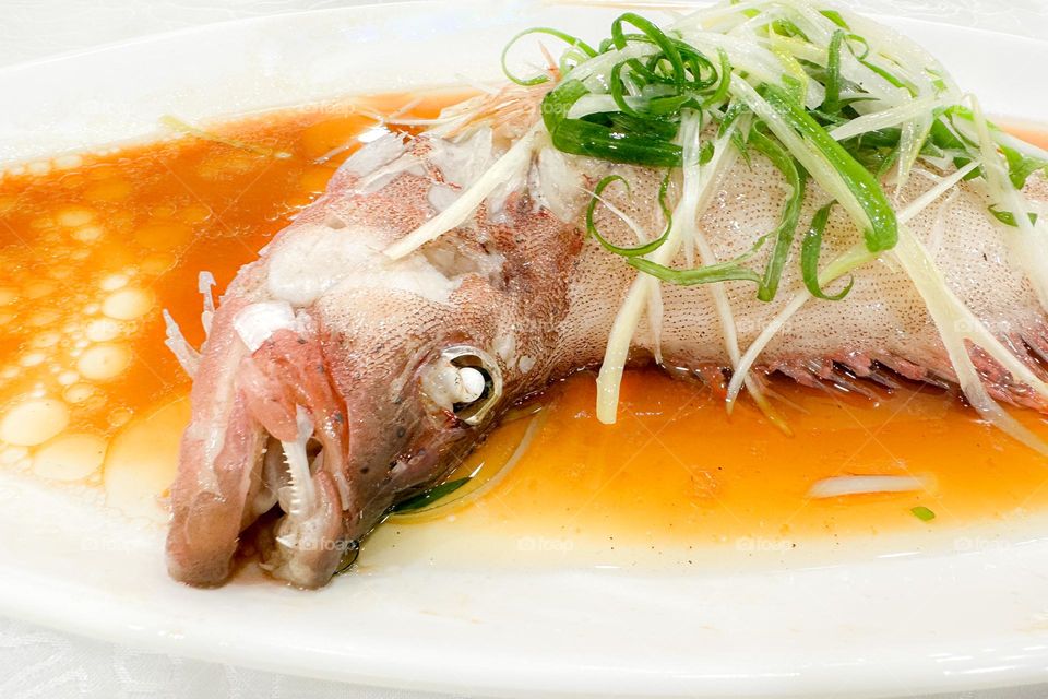 Steamed whole fresh fish with soy sauce and scallions, a delicacy in Chinese/Cantonese cuisine, and very delicious despite appearances and inclusion of fish head
