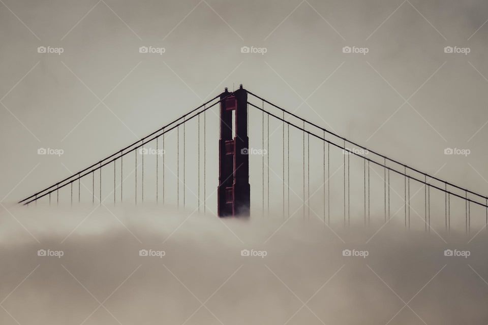 Sepia style image of the Golden Gate Bridge with the beautiful fog cascading right across the middle of the classic bridge within its art deco design welcoming people to the San Francisco Bay in California 