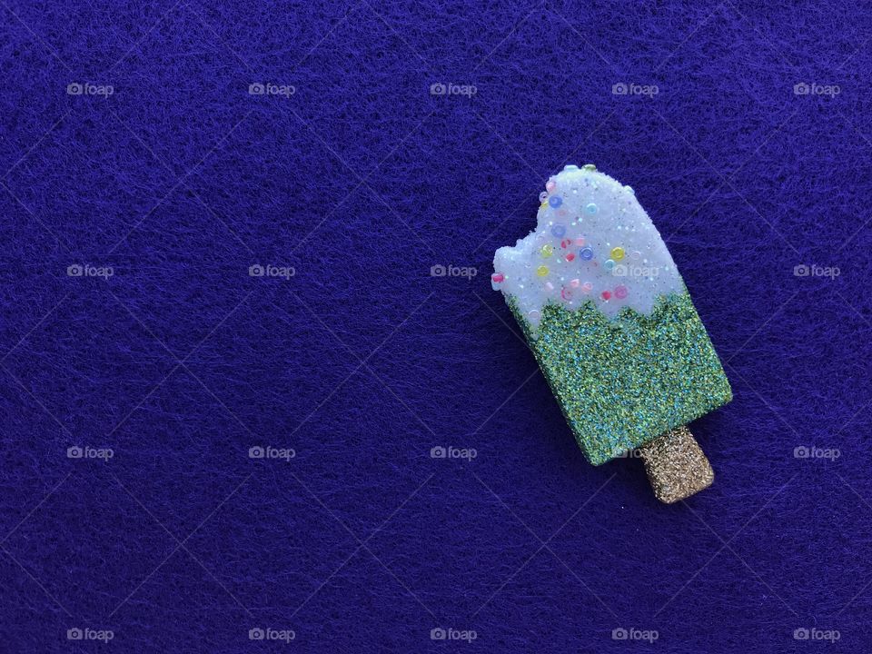 A small glittery green ornament on a blue piece of felt!