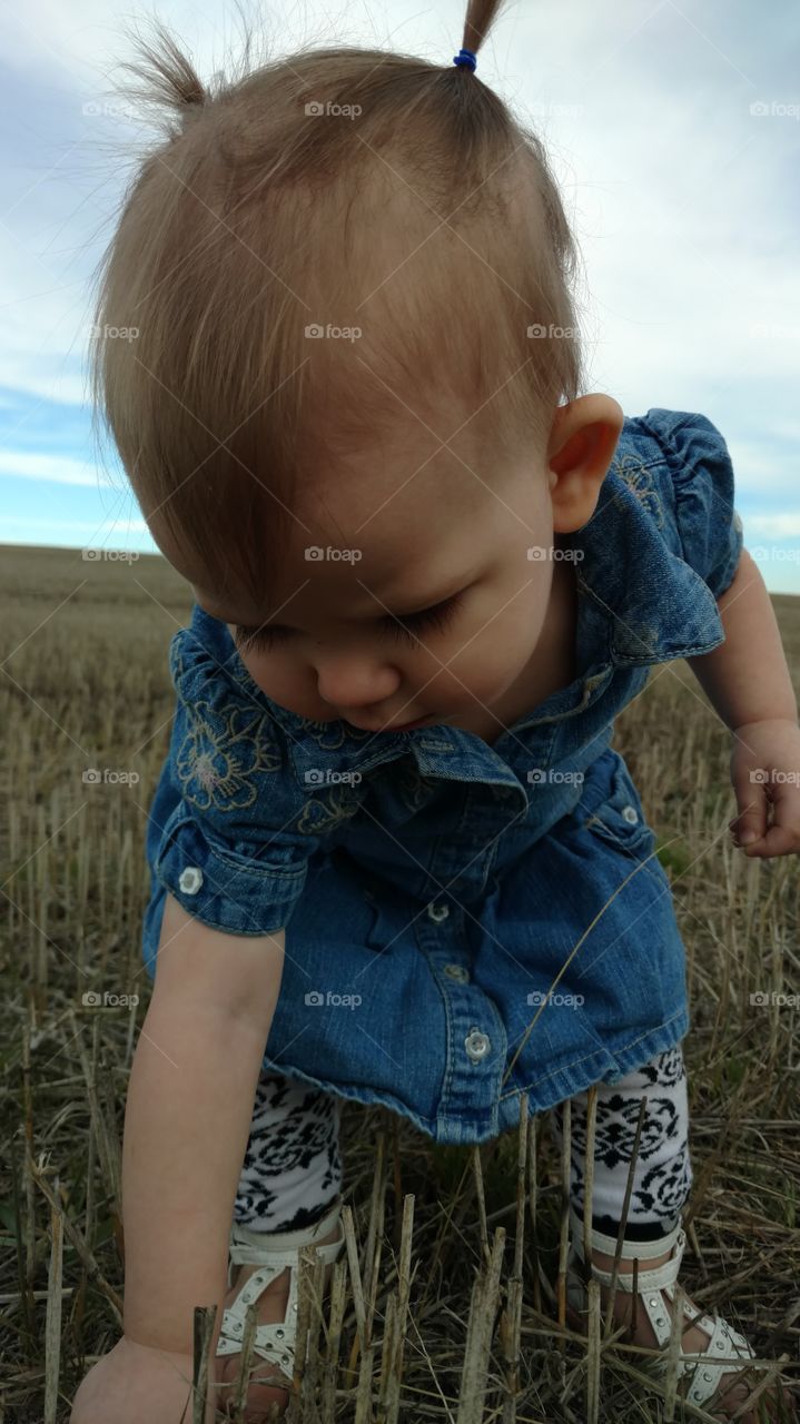 Baby with piggytail in field