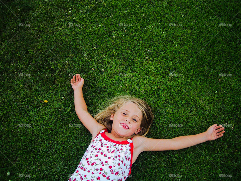 Girl happily laying in the grass is n a warm summer day.