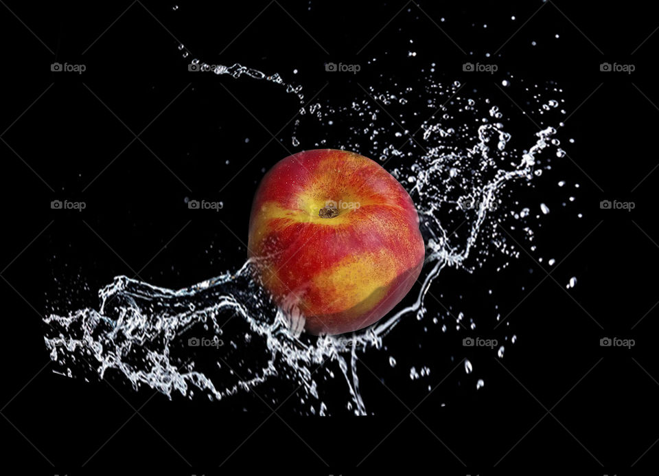 Nectarine in water splashes on Black background