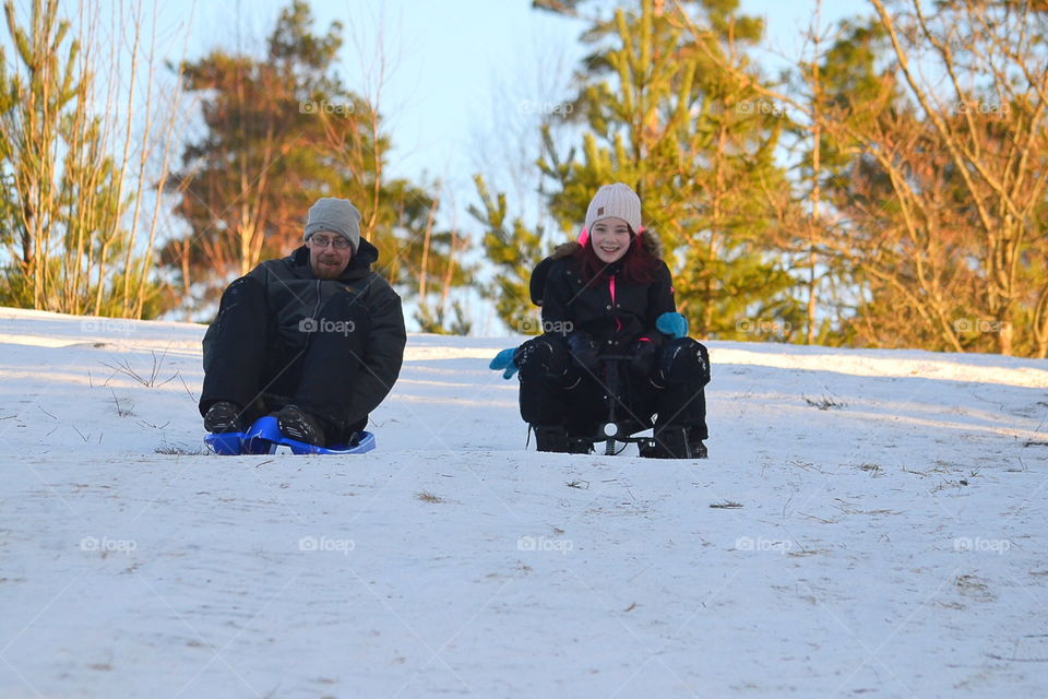 Father and daughter going down the hill in their sledge