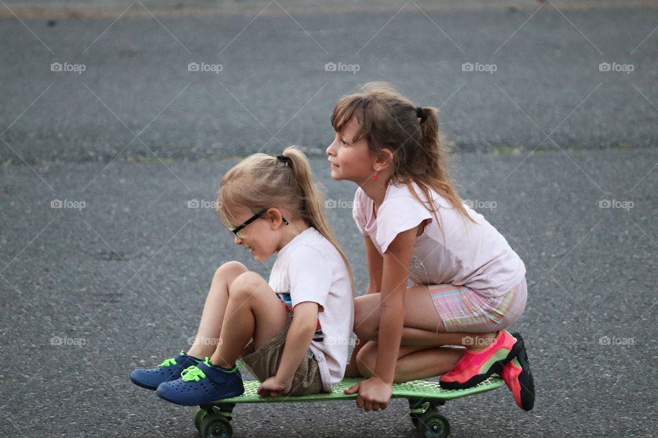Sisters taking a ride on a skateboard