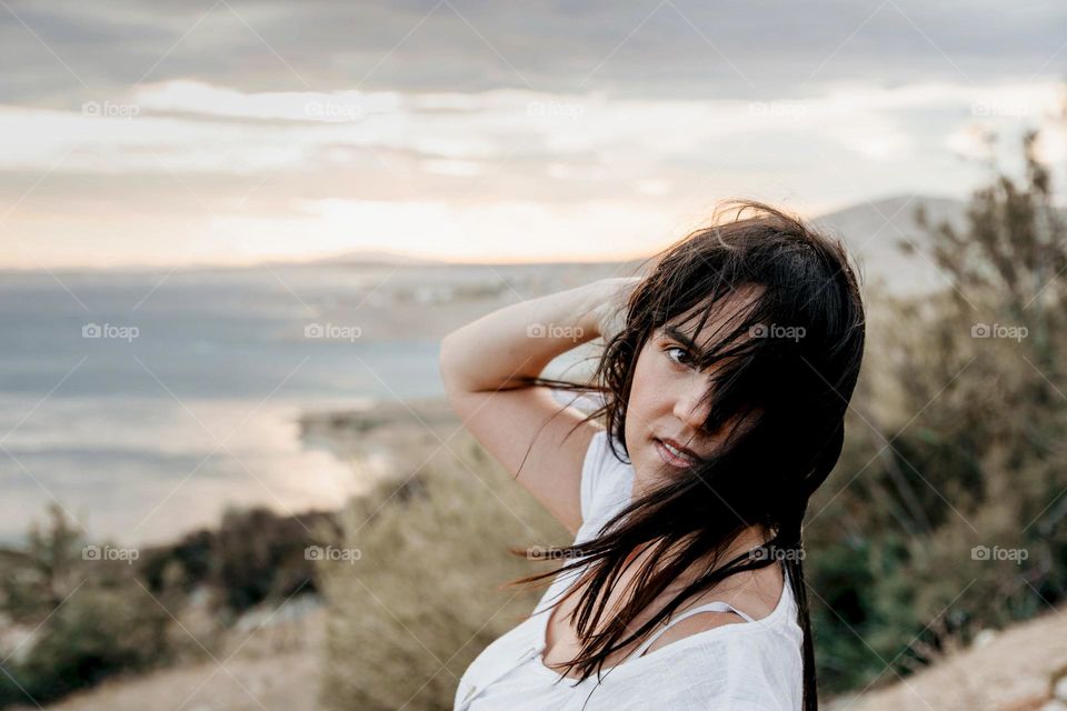 Portrait of beautiful young woman with wind in hair on the coast of sea