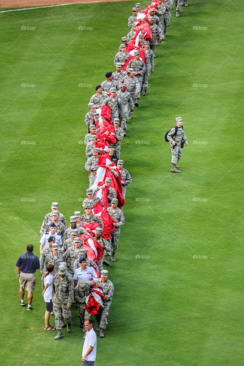 Working together. Soldiers carrying a giant USA flag to unroll on the field at globe life park in Arlington Texas during 4th of July 