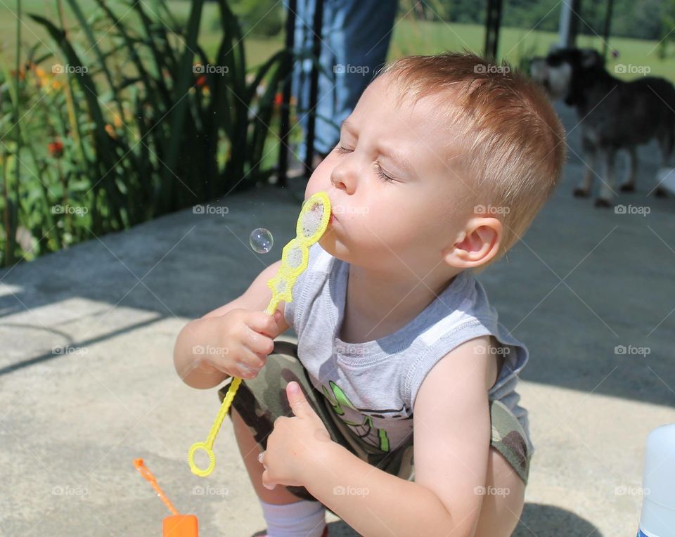 Cute boy blowing bubbles through bubble wand