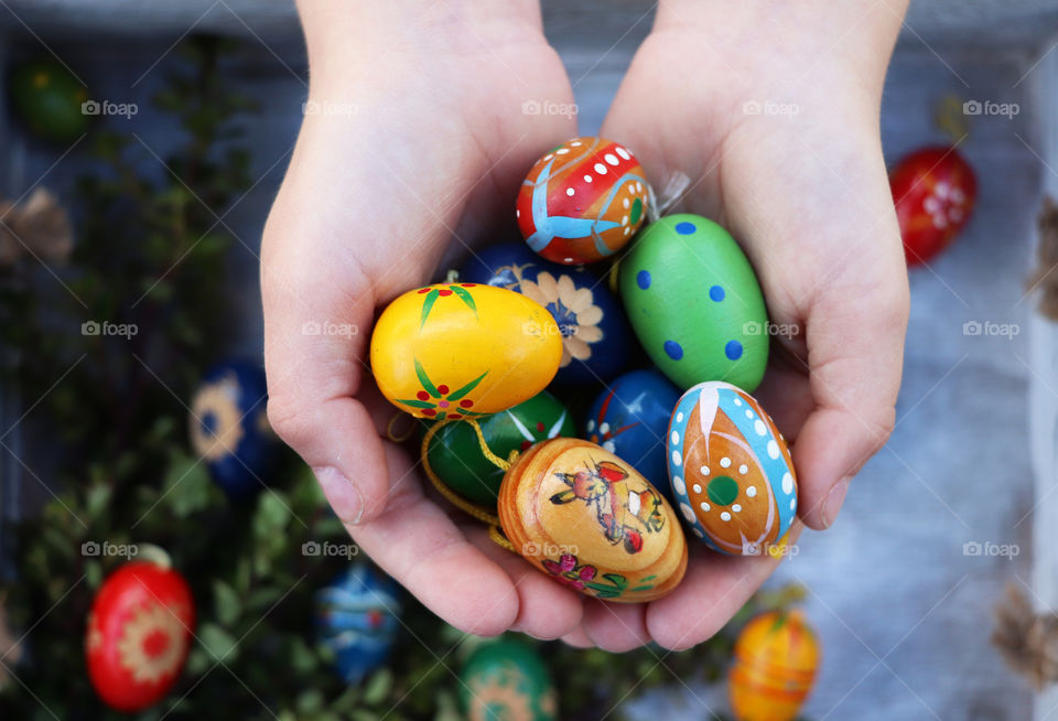 A child's hand holding a bunch of Easter eggs