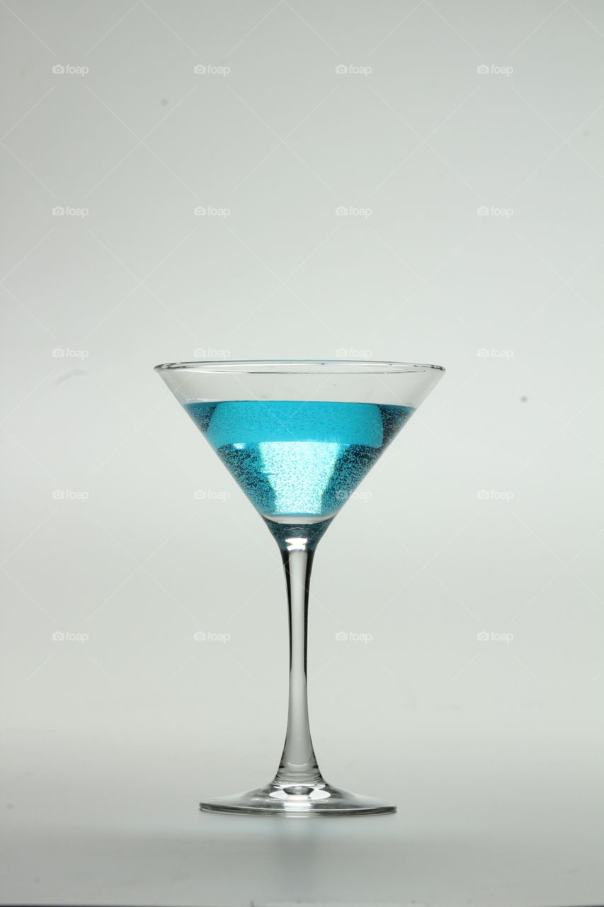 Blue mixed drink in a martini glass. 