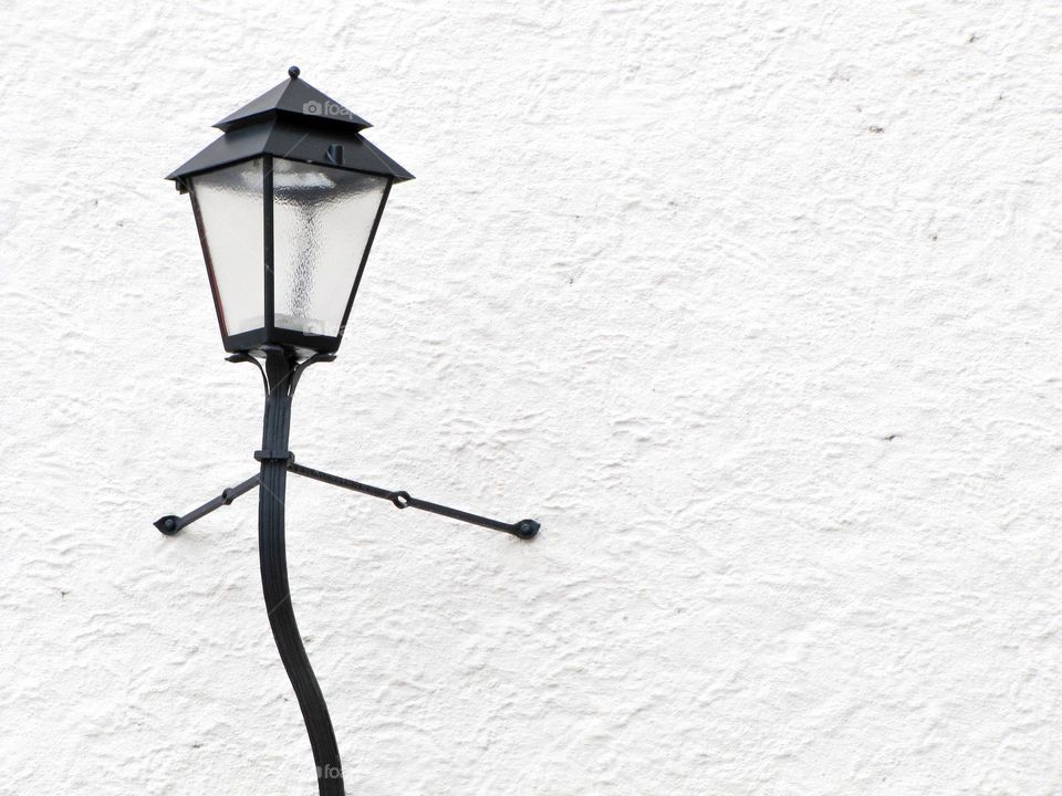 Farola posando sobre pared blanca.