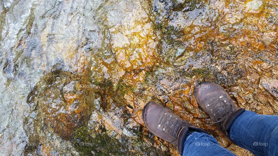 river water over golden stones get wearing hiking boots