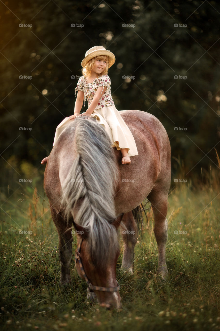 Little girl with horse at summer evening 