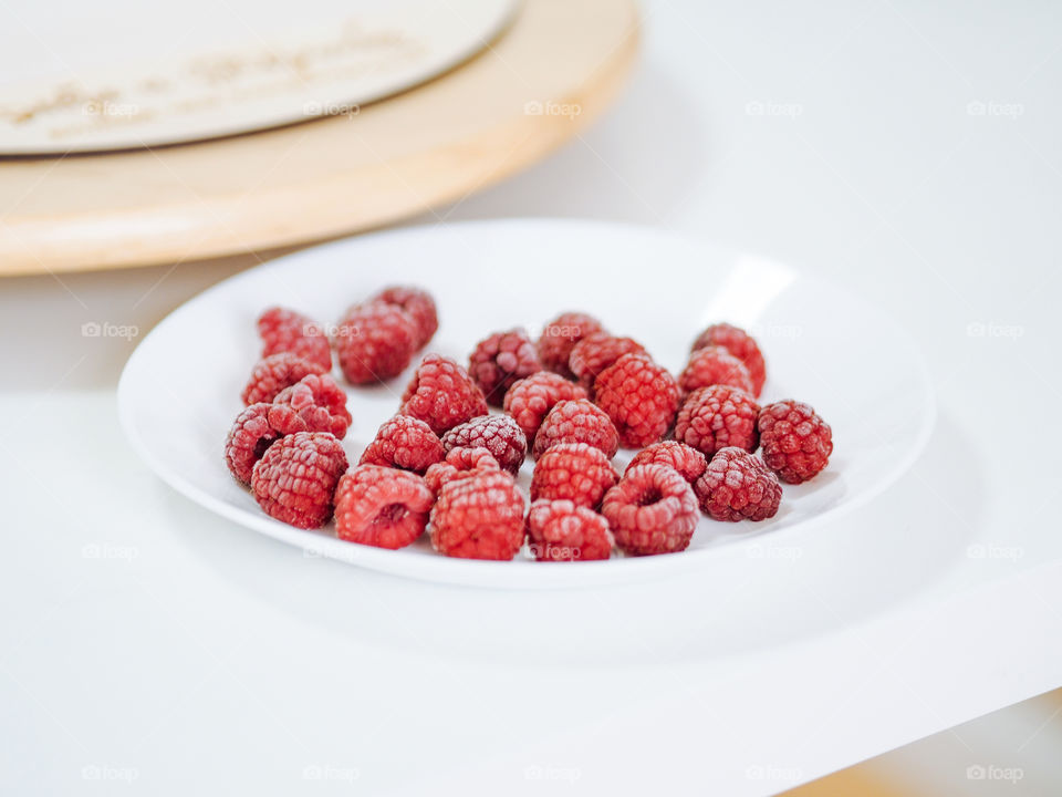 Frozen raspberries in white plate 