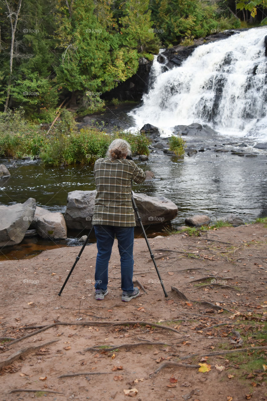 Woman photographing a waterfall