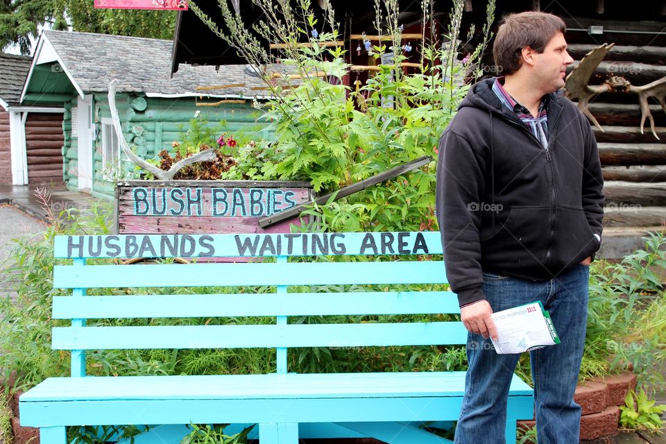 Man standing near wooden bench in park