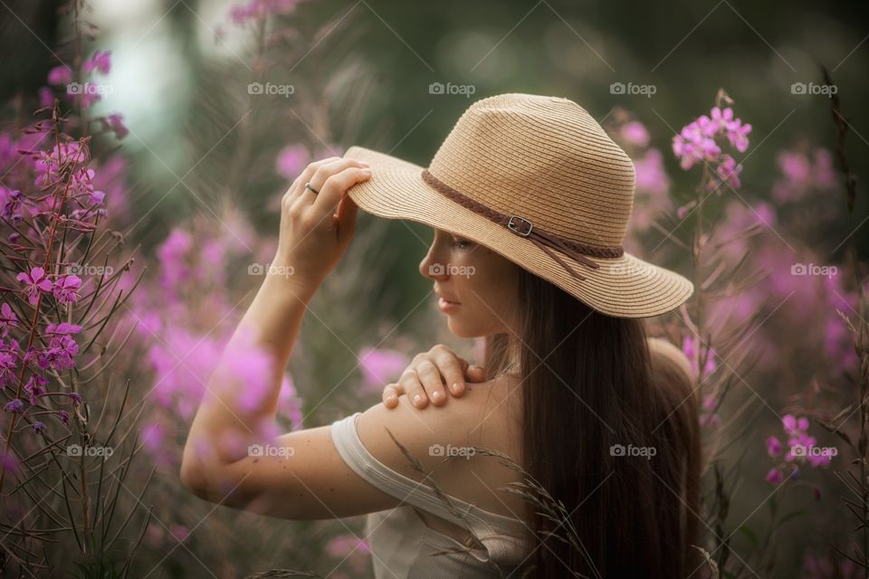 Beautiful young woman in a field of blossom flowers in boho style