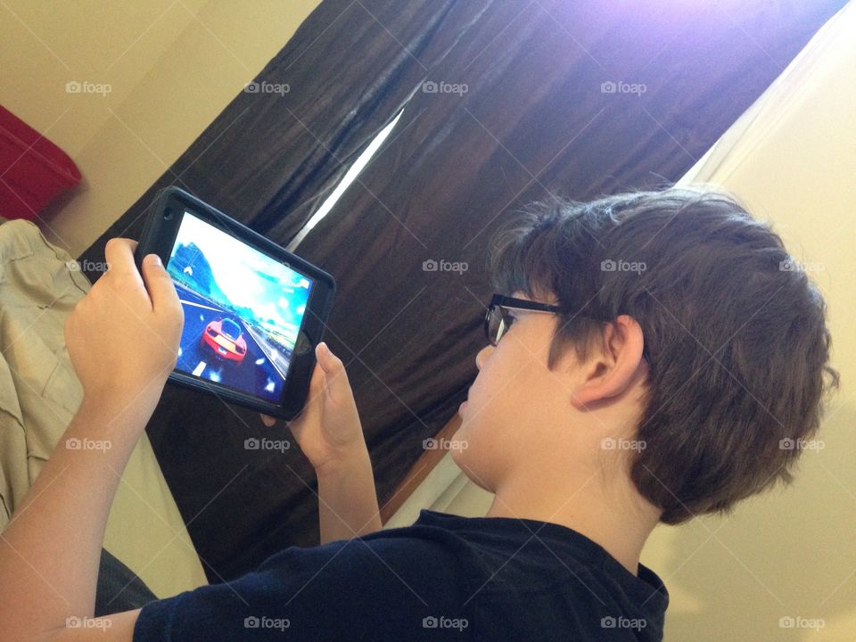 Boy playing red race car game in his iPad 