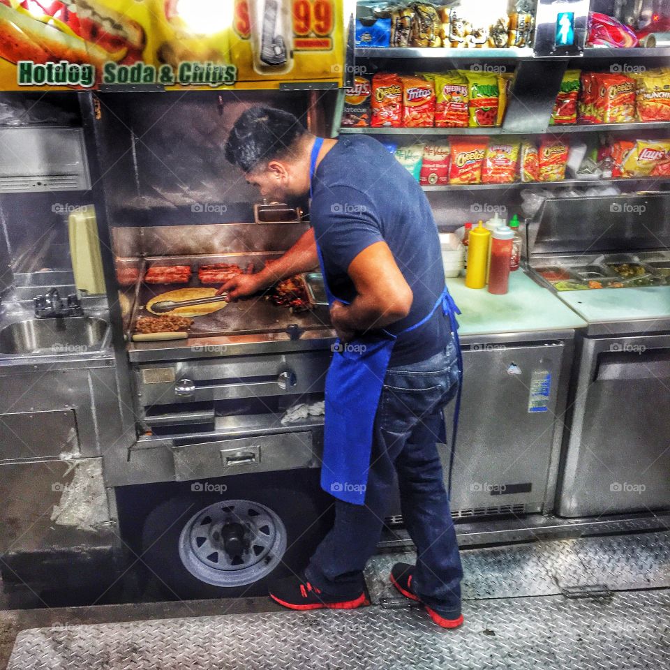 Street Vendor. A man at a food truck preparing hot dogs