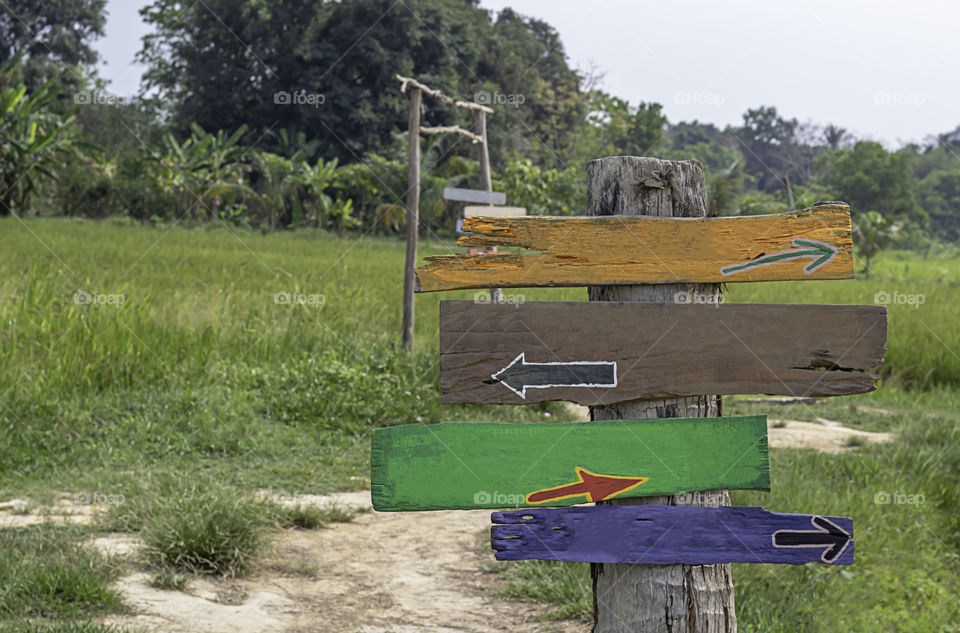 Wooden painted signs on poles Background fields and trees.